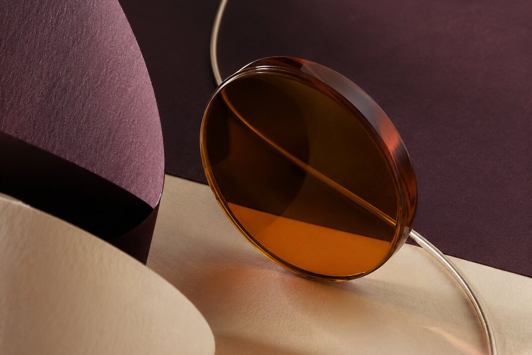 Détail abstrait de verre ambré et papiers prune et ivoire
